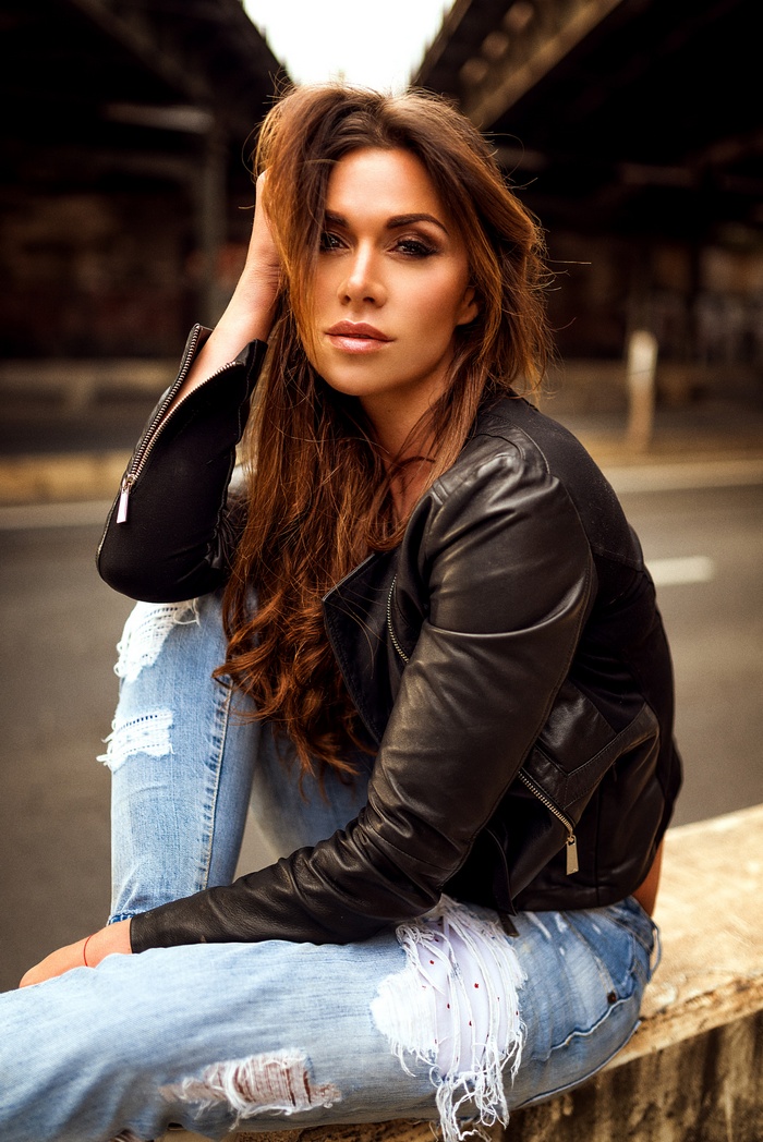 Woman with long hair wearing a leather jacket and torn jeans