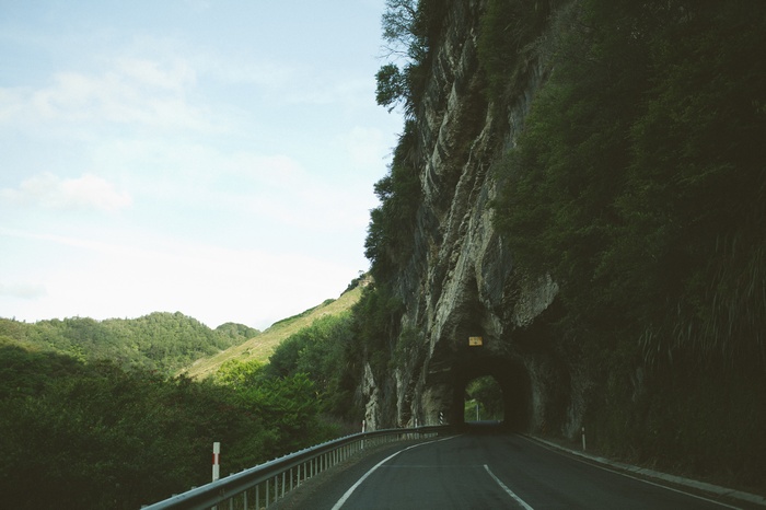 Road leading into a tunnel through a rocky cliffside