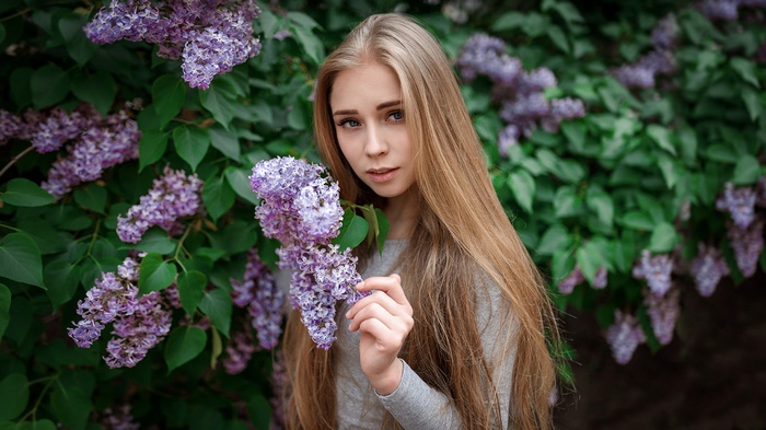 Young woman with long blonde hair near lilac bush