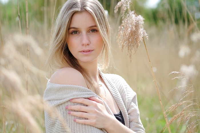 Woman in a cardigan in a field of tall grass