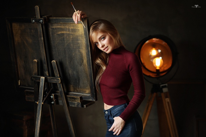 Woman with paintbrush by easel