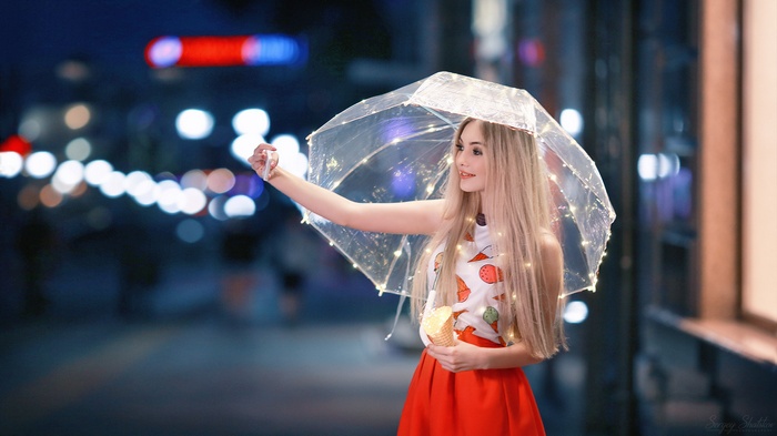 Woman with umbrella and ice cream at night