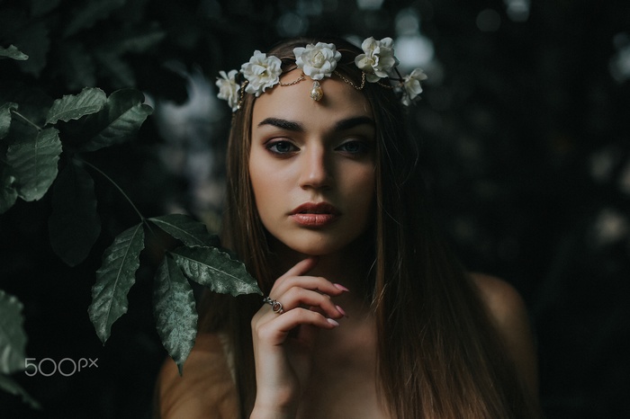 Woman with flower crown in dark forest