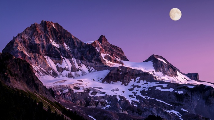 Snow-capped mountains under a purple sky with a full moon