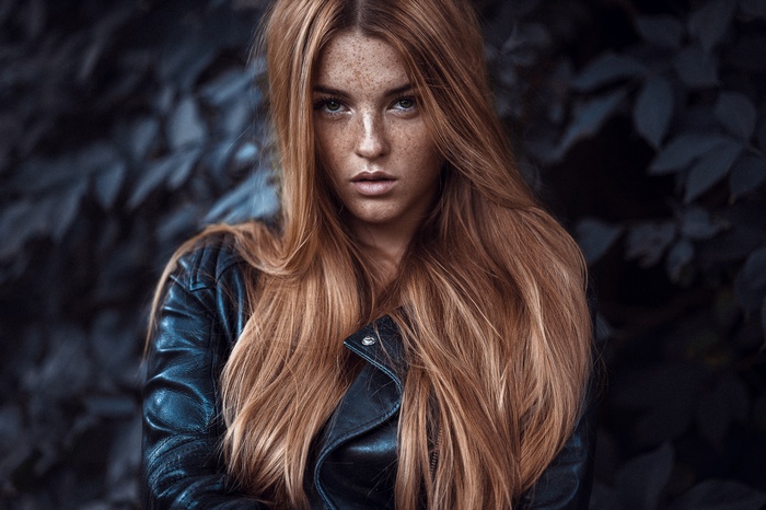 Woman with long blonde hair and freckles wearing a leather jacket