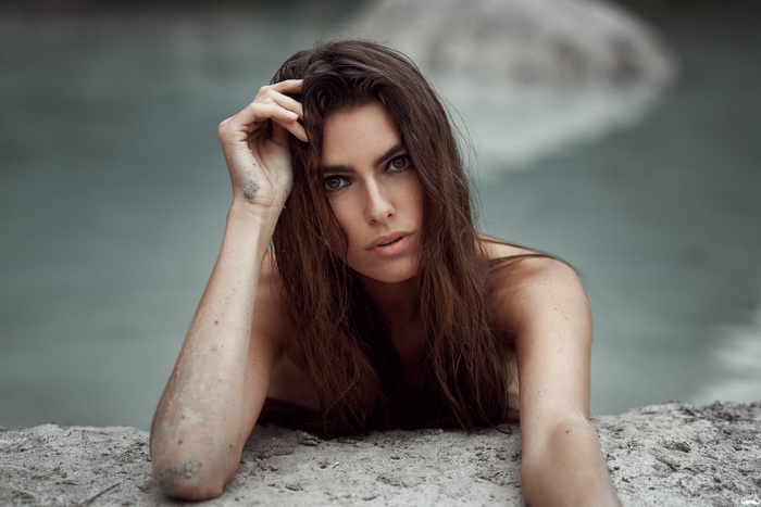 Woman with hand on head by water