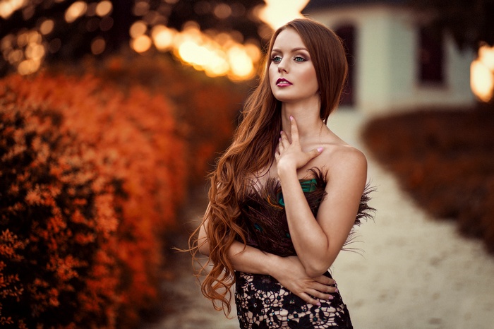 Woman with long red hair and peacock dress outdoors