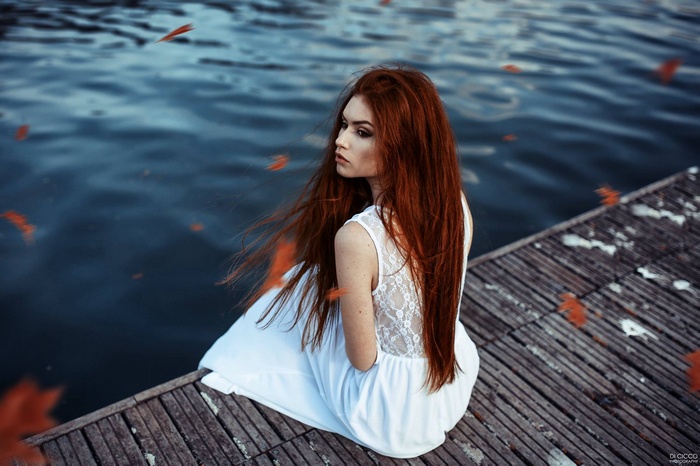 Redhead woman in white dress sitting on a dock