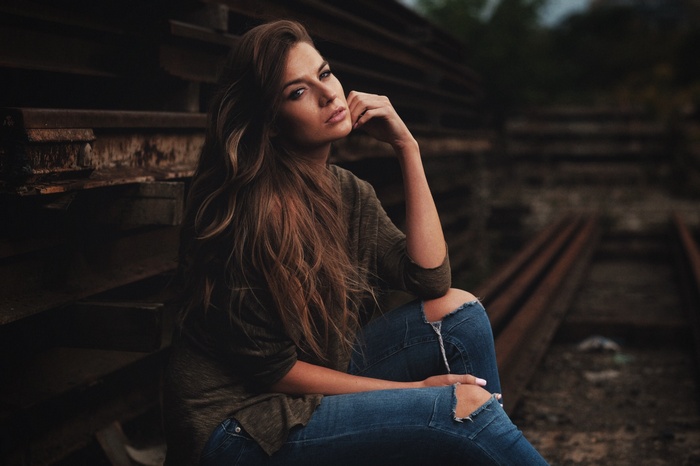 Woman in torn jeans sitting outdoors