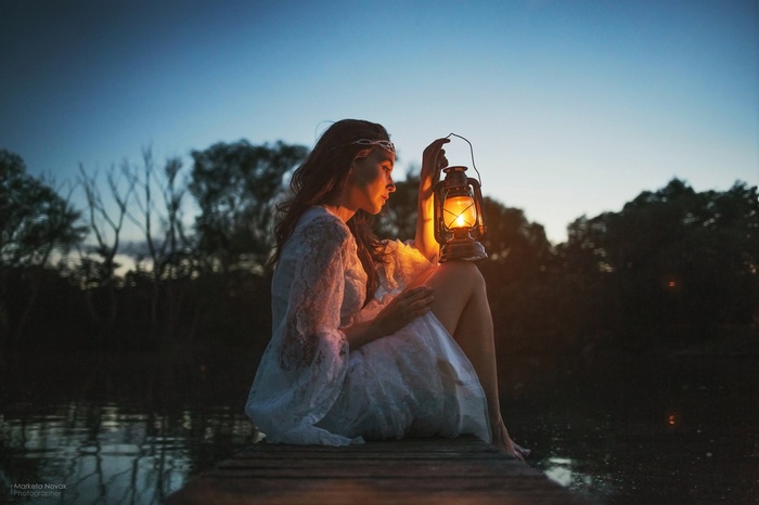 Woman sitting on a dock with a lantern