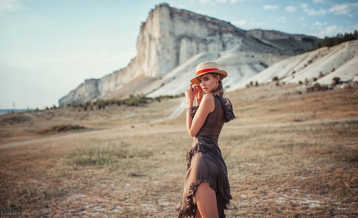 Woman in a straw hat and dress in front of a white cliff