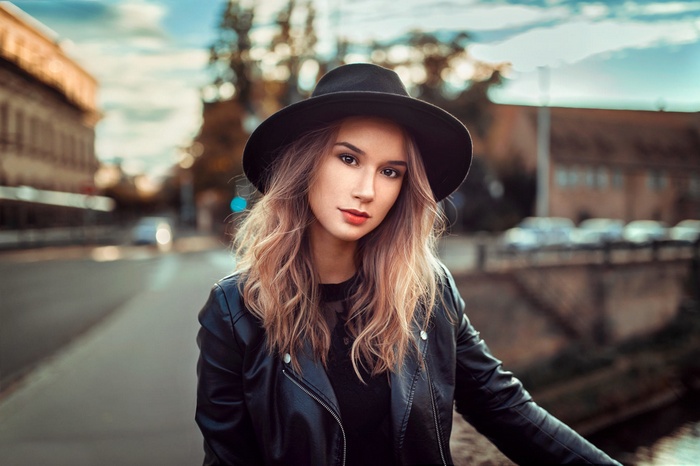Woman in black hat and leather jacket outdoors