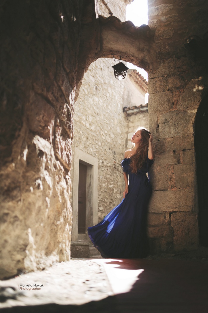 Woman in blue dress in ancient stone alley