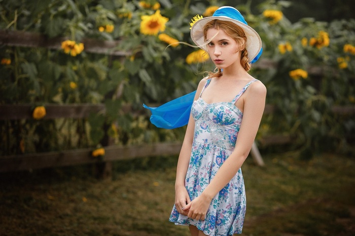 Woman in a floral dress and hat in a garden