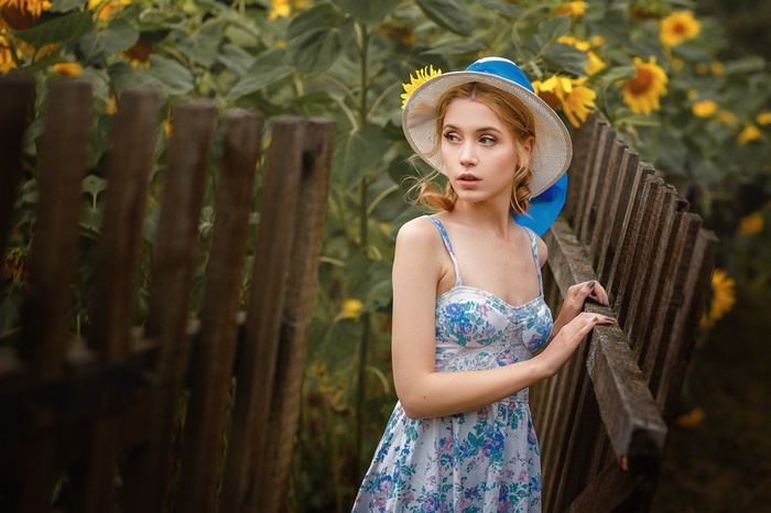 Woman in a hat and dress in a sunflower garden