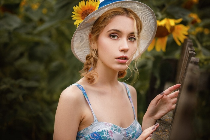 Woman with sunflower in hat in garden