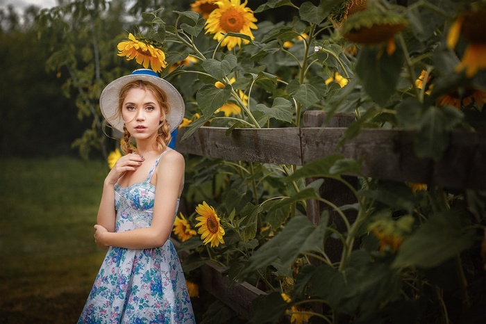 Woman in a dress and hat in a sunflower garden