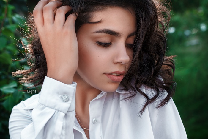 Woman in white shirt with hand in hair