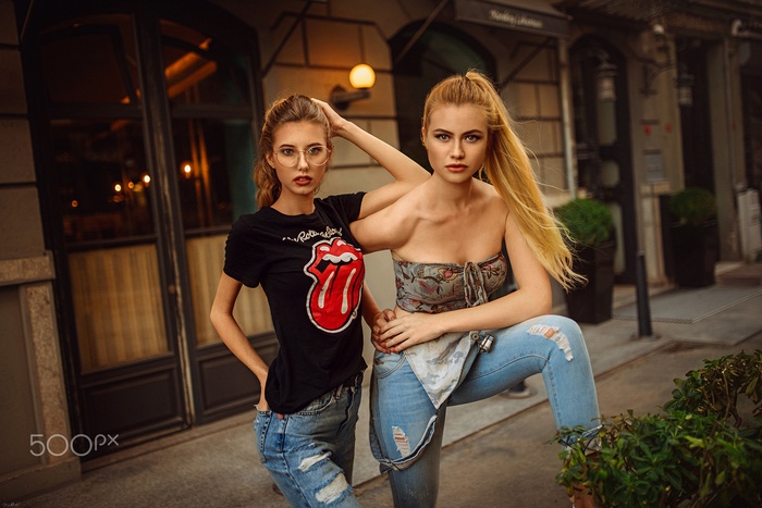 Two young women wearing ripped jeans and t-shirts outdoors