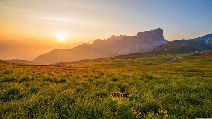 Sunrise over a mountain valley with green fields