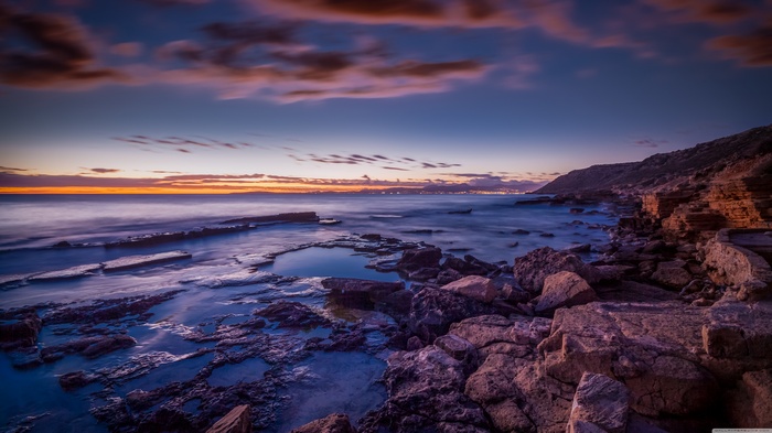Rocky coastline at sunset with ocean waves