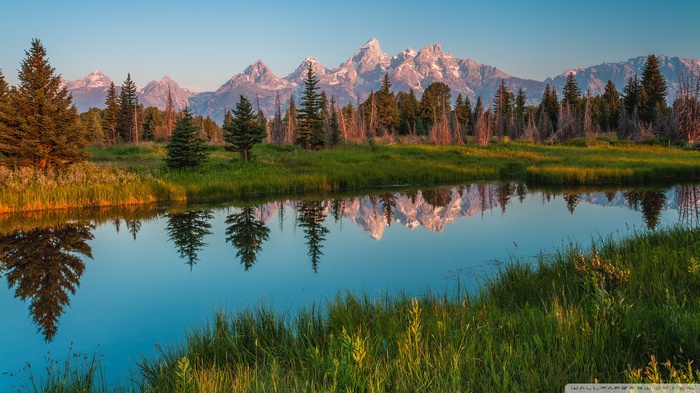 Grand Teton Mountains reflected in a calm river at sunrise