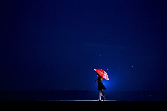 Girl with red umbrella walking at night