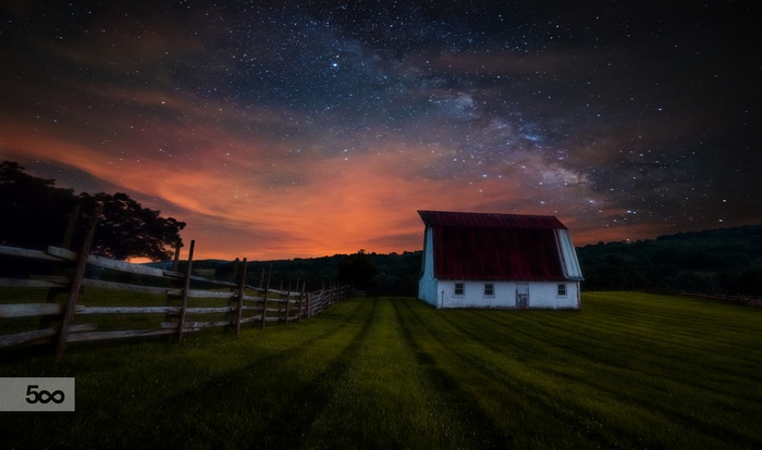 Barn under the Milky Way with a wooden fence