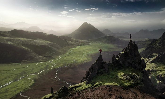 Two people on rocky peaks overlooking a valley