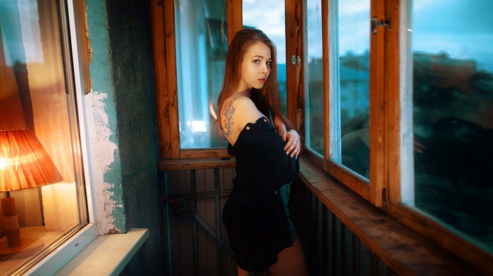 Woman with tattoo standing by a window
