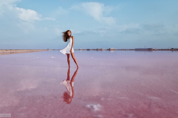 Woman in white dress standing in pink salt lake
