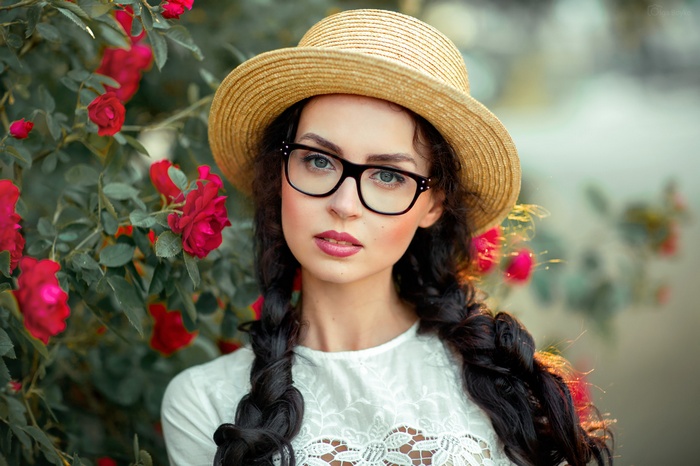 Woman with glasses and hat in front of roses