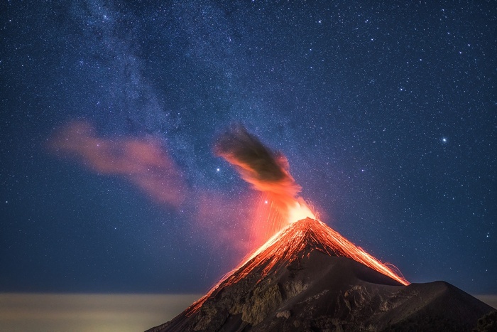 Volcanic eruption under a starry night sky