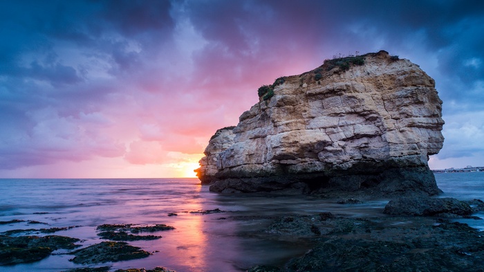 Coastal rock formation at sunset with ocean waves