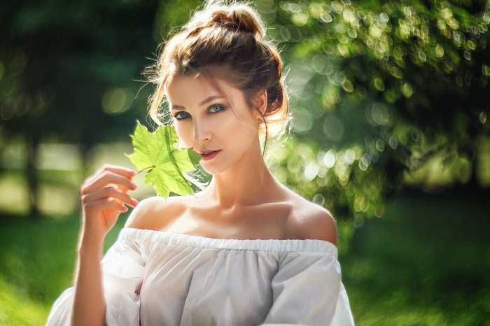Woman holding a green leaf outdoors
