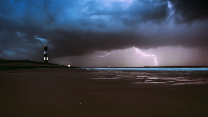 Lighthouse during a lightning storm over the ocean
