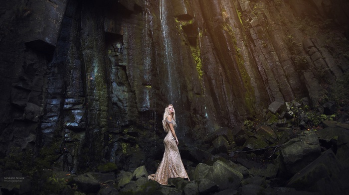 Woman in a sequined dress by a waterfall