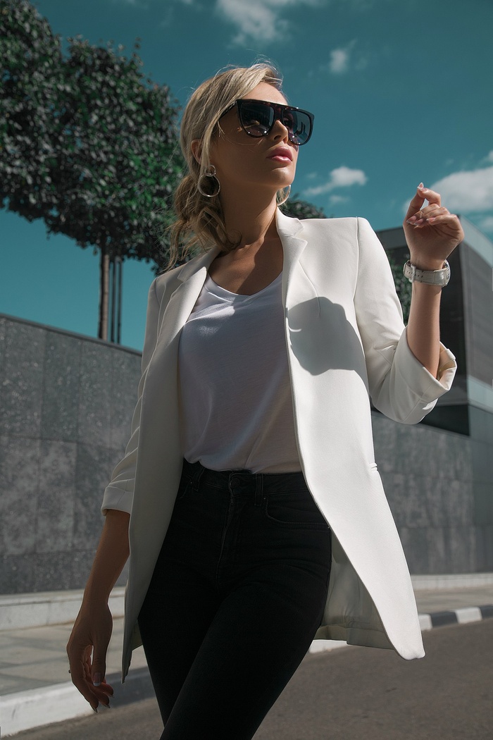 Woman in white blazer and sunglasses outdoors