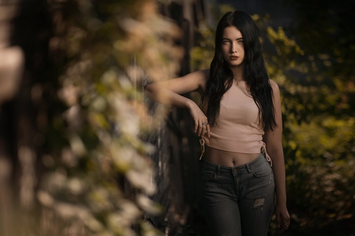 Woman in crop top and torn jeans leaning on a railing