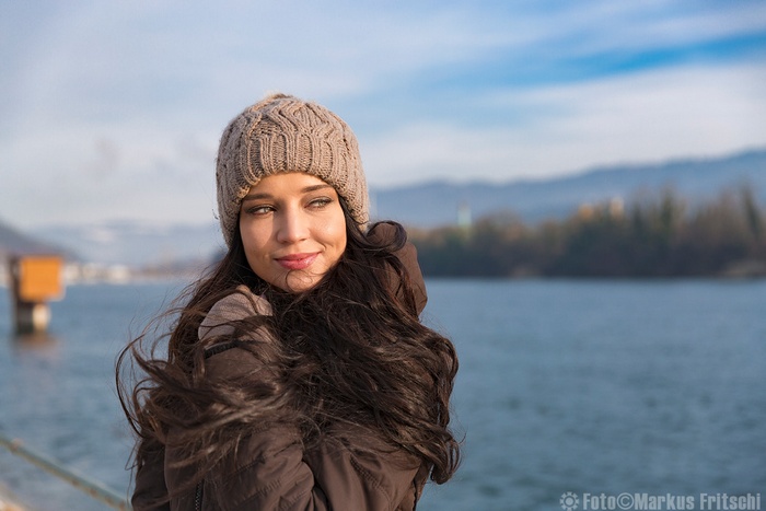 Woman in hat and jacket by the water