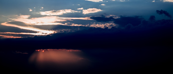 Sunset sky with dark clouds and sunbeams