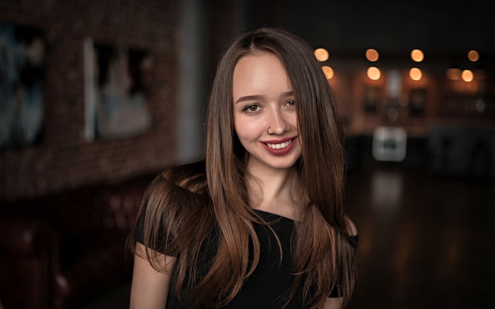 Woman with long brown hair and nose ring smiling