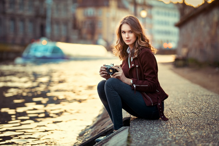 Woman with camera sitting by canal