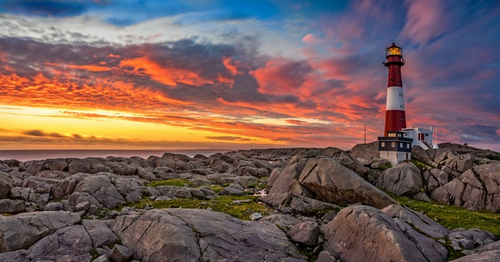 Lighthouse on rocky shore at sunset