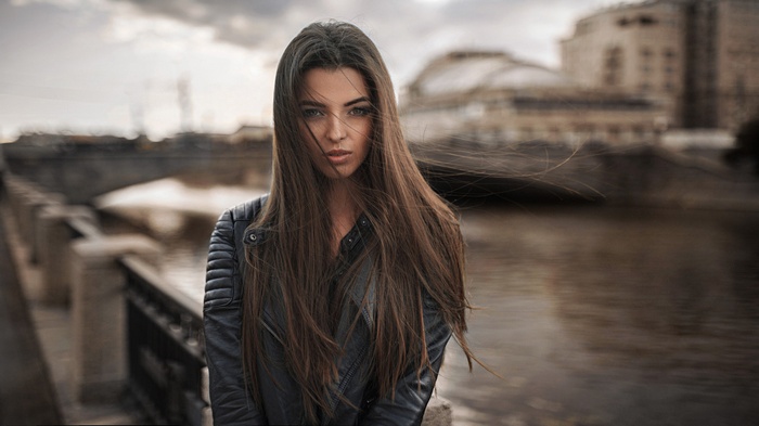Woman with long hair wearing a leather jacket by a river