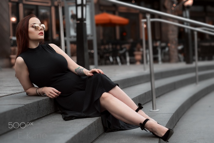 Woman in black dress and glasses by E. Kane