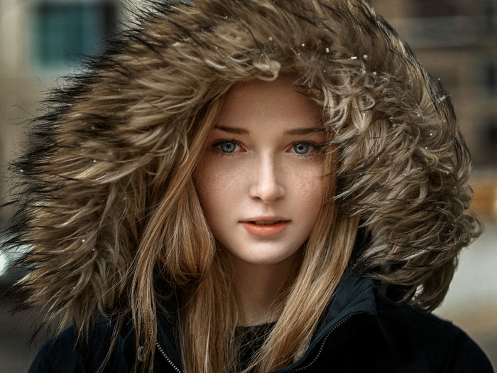 Woman with blonde hair and blue eyes wearing a fur-lined hood