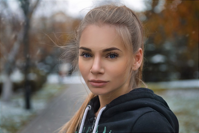 Woman with blonde ponytail and blue eyes in a black hoodie