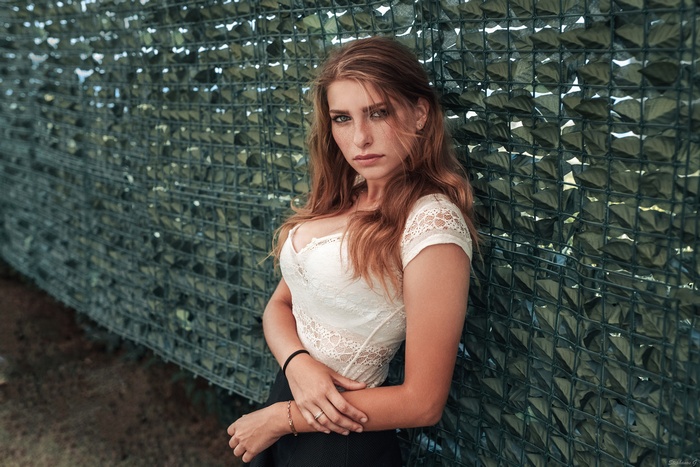 Woman with red hair leaning against a fence