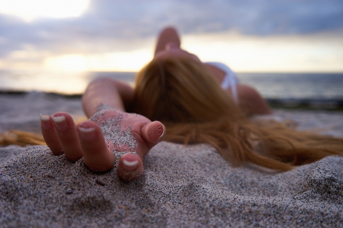 Woman with long hair lying on sand at beach